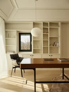 A modern home office featuring a wooden desk, bookshelf, and comfortable chair.