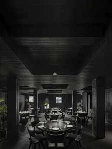 Circular tables and chairs in a minimalist restaurant interior with dark wooden flooring and ceiling.