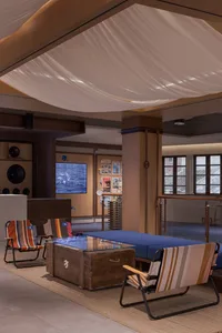 An industrial-style reception lounge with a textured canvas ceiling, wooden floor, and glass coffee table.
