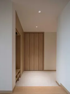 A modern industrial corridor with minimalist wooden cabinets and white walls.