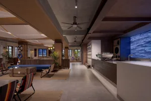 Modern lobby interior with concrete finishes and industrial design elements, featuring a central desk area, seating, and a mo