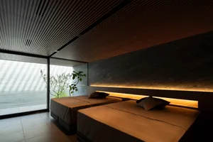 Modern, minimalist hotel room with concrete and marble finishes and two single beds.