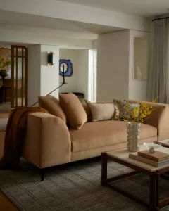 Modern living room with neutral-toned furniture and fabric, featuring a comfortable sofa with throw pillows, wood coffee tabl