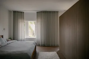 Modern minimalist bedroom with soft, neutral textiles and wooden accents.