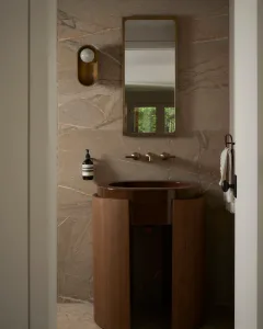 Modern bathroom with marble walls, wooden vanity, and brass fixtures