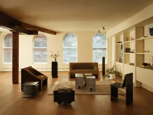 A modern living room featuring wooden flooring, a minimalist sofa, and sleek, geometric furniture.
