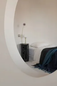 Minimalist bedroom with transparent vase and glass bedside table.