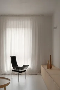 A minimalist bedroom with neutral materials and a large window.