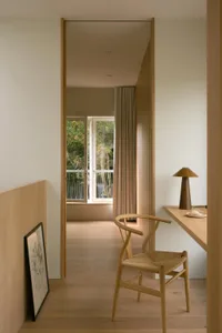A minimalist office space with wooden furniture and a large window overlooking trees.
