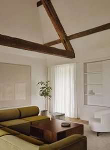 A minimalist living room featuring a modern sofa, wooden coffee table, and a large window with sheer curtains.