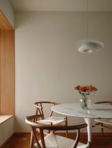 A minimalist dining room with a marble table and wooden chairs.