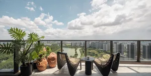 A modern balcony featuring concrete furniture, plants in pots, and a view of a cityscape.