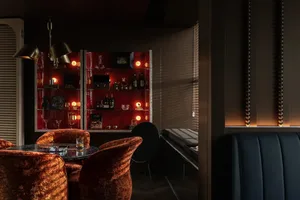Modern bar interior featuring red acrylic walls and metallic finishes.