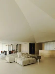 A modern, minimalist living room with a large, neutral-toned leather sectional sofa, a round coffee table, and a sleek, minim