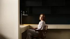 A modern desk setup featuring a wooden chair and a sleek, contemporary lamp.