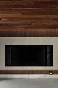 A modern living room featuring a sleek, black television mounted on a wall with wood paneling.