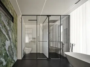 Modern bathroom featuring marble walls, glass shower enclosure, and freestanding bathtub with floor-to-ceiling window.