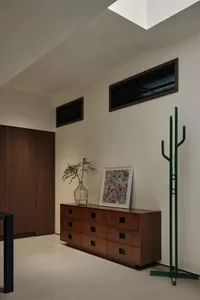 現代簡約玄關，搭配木製抽屜、玻璃花瓶與抽象藝術作品。