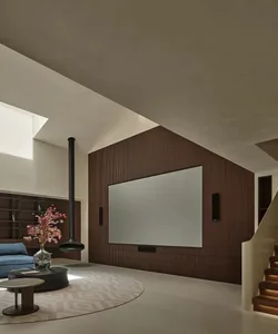 A minimalist living room featuring a wood-paneled wall with a large screen, a modern coffee table with a vase of flowers, and