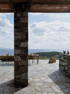 A minimalist outdoor patio with stone and wood elements overlooking the sea.