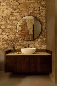Modern bathroom with stone wall, wooden vanity, and marble countertop.