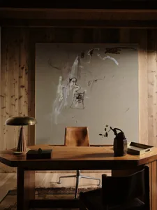 Modern office space featuring wooden desk, brass lamp, and abstract art
