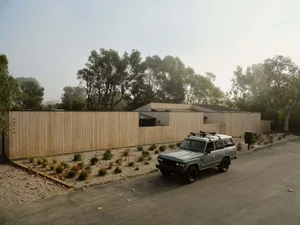 A modern residential exterior featuring a wood-paneled fence and house.