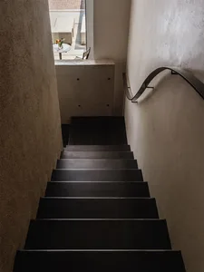 A modern metal staircase with a curved handrail in an interior space.