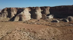 A desert camp with canvas tents arrange on the sandy ground.