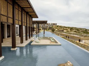 Modern hotel lobby with concrete pool and seating area.