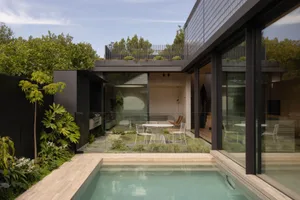 Modern house exterior featuring a glass swimming pool and garden.