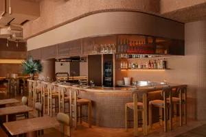 Modern restaurant bar with tiled walls, marble countertops, and concrete bar stools.