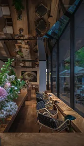 A cozy cafe interior with wooden tables and chairs, canvas seats, and potted plants.