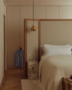 A modern bedroom featuring a fabric-covered bed and marble nightstand.