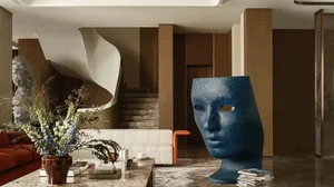 A modern living room with a large blue metallic mask and a flower arrangement on the table