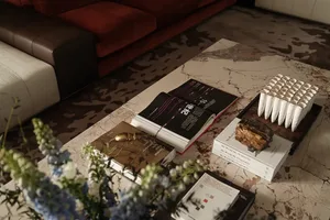 A modern coffee table with a marble surface, books, and decorative items on it.
