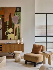 A modern lounge area featuring a cozy chair, side table, and abstract artwork