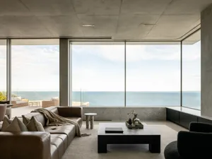 Modern living room featuring a large glass window overlooking the ocean.