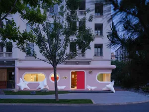 A modern architectural storefront with a concrete facade and large, artistic wooden doors.