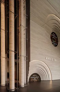 A modern exhibition space featuring large ceramic columns illuminated by warm light.