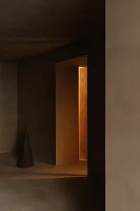A minimalist hallway with smooth concrete walls and floor, illuminated by warm, natural light.