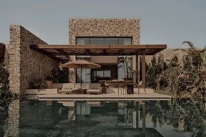 Modern residential exterior featuring stone walls, concrete patio, and a tranquil poolside area.
