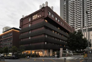 A modern hotel building with a brick exterior and illuminated signage.