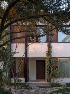 A minimalist residential home with wooden exterior, glass windows, and concrete features.