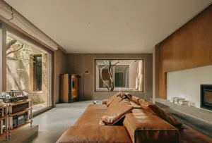 A modern living room with a brown leather sofa and wooden elements.