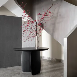 A stylish entryway featuring a black round table with an elegant vase containing decorative red berries, set against a modern