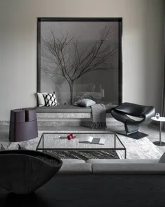 A modern interior design featuring a concrete bench with glass inserts, a black leather armchair, and a glass table.