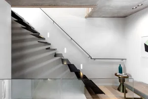 A modern interior with a metal staircase leading to an unseen floor.
