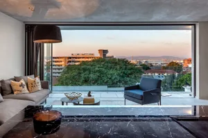 Modern living room with concrete floor, glass walls, and minimalist furniture.