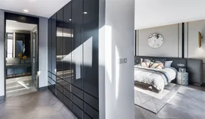 Modern bedroom with wooden floors, gray walls, and a large bed.